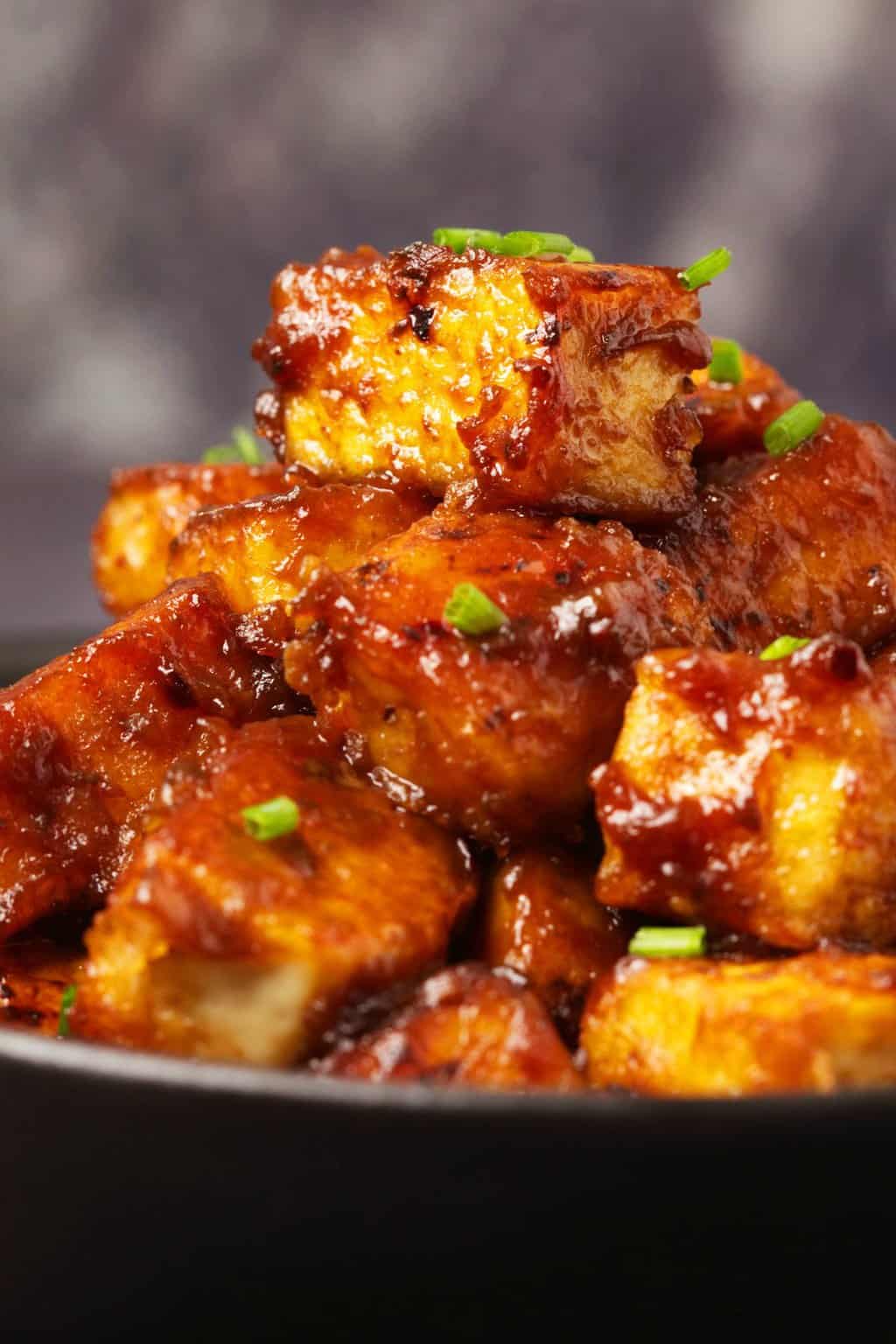 Le tofu du général Tso garni de ciboulette hachée dans un bol noir. 