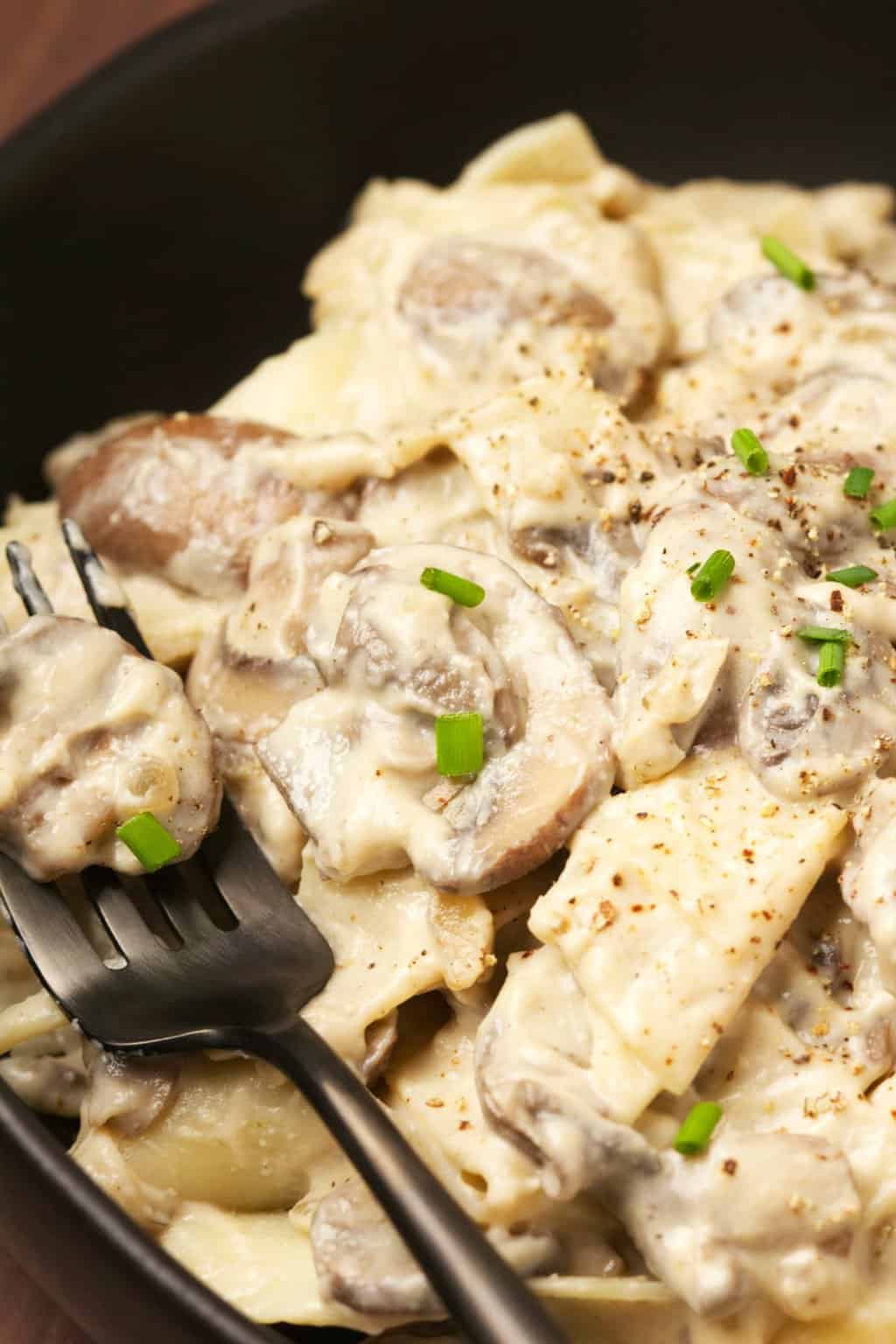 Stroganoff aux champignons végétalien garni de ciboulette hachée dans un bol noir.