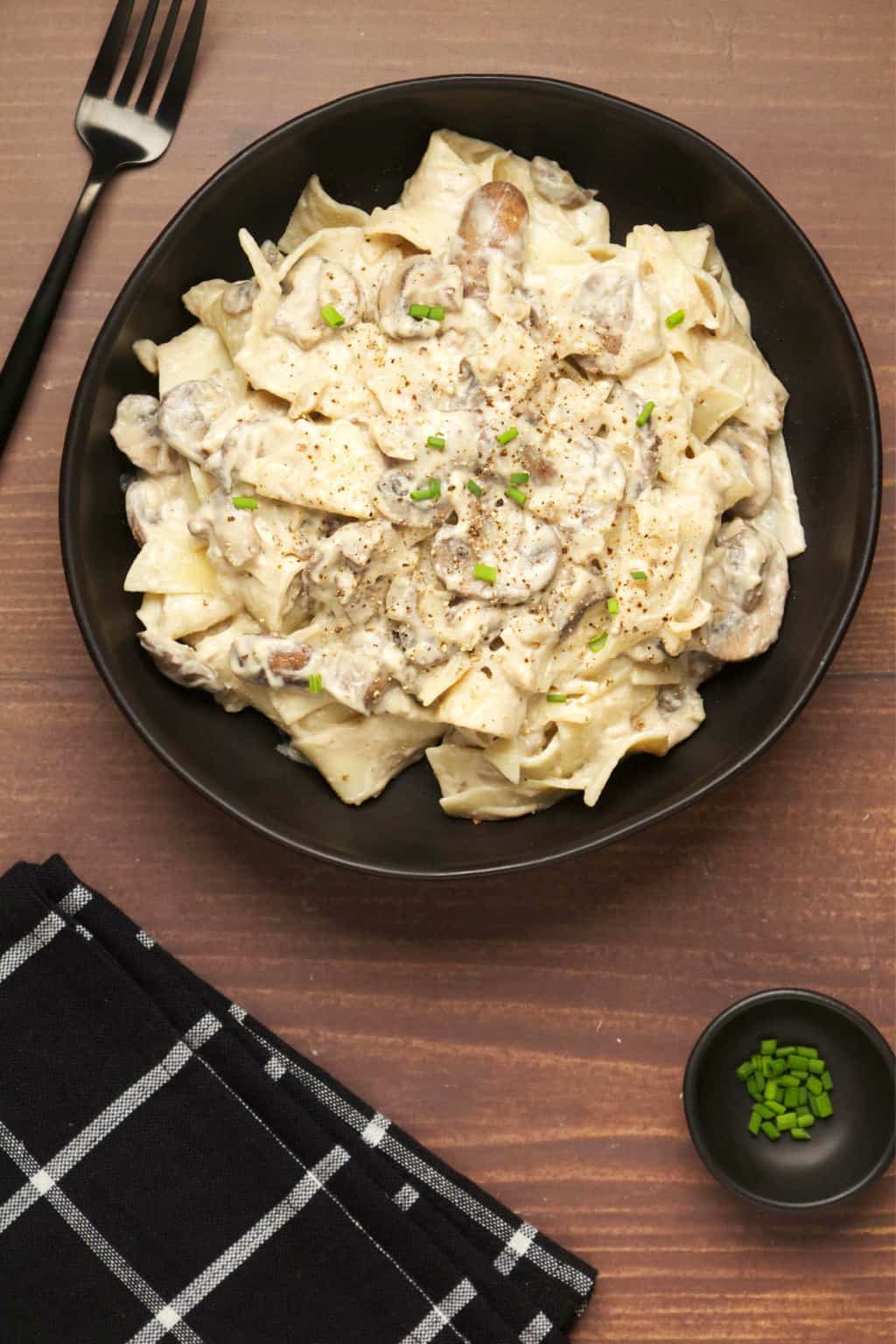 Stroganoff aux champignons végétalien garni de ciboulette hachée dans un bol noir.