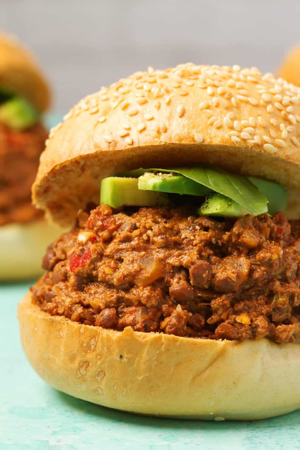 Vegan Sloppy Joe garni d'avocat en tranches et de feuilles de basilic frais. 
