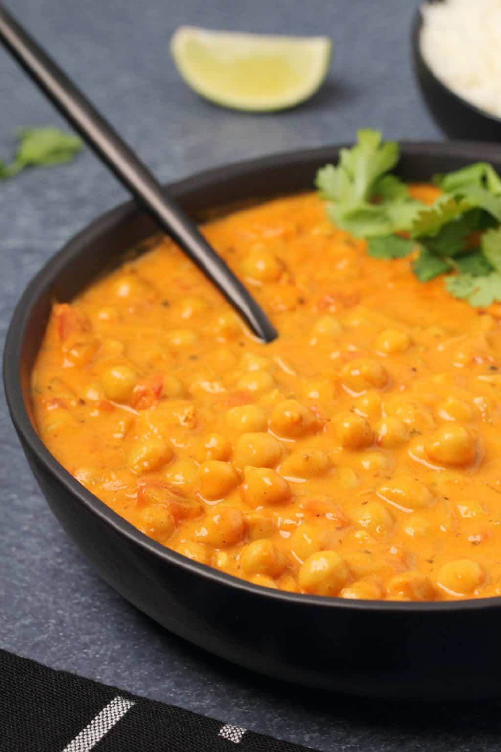 Curry de pois chiches végétalien dans un bol noir avec une cuillère.