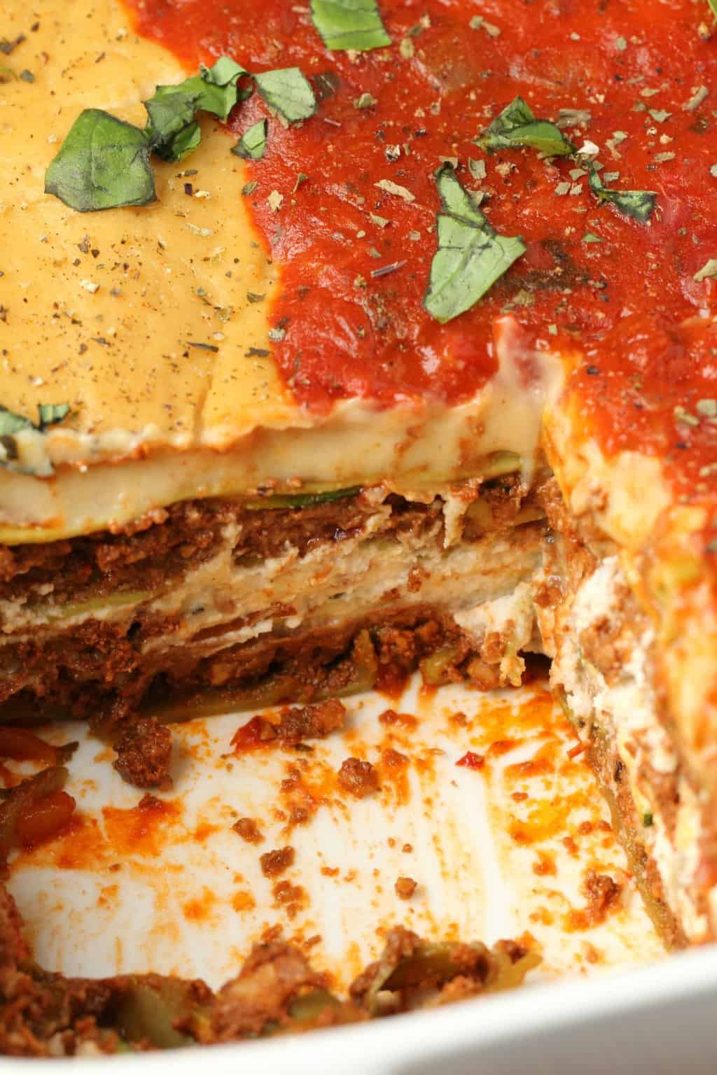 Lasagne végétalienne dans un plat blanc avec une tranche retirée. 