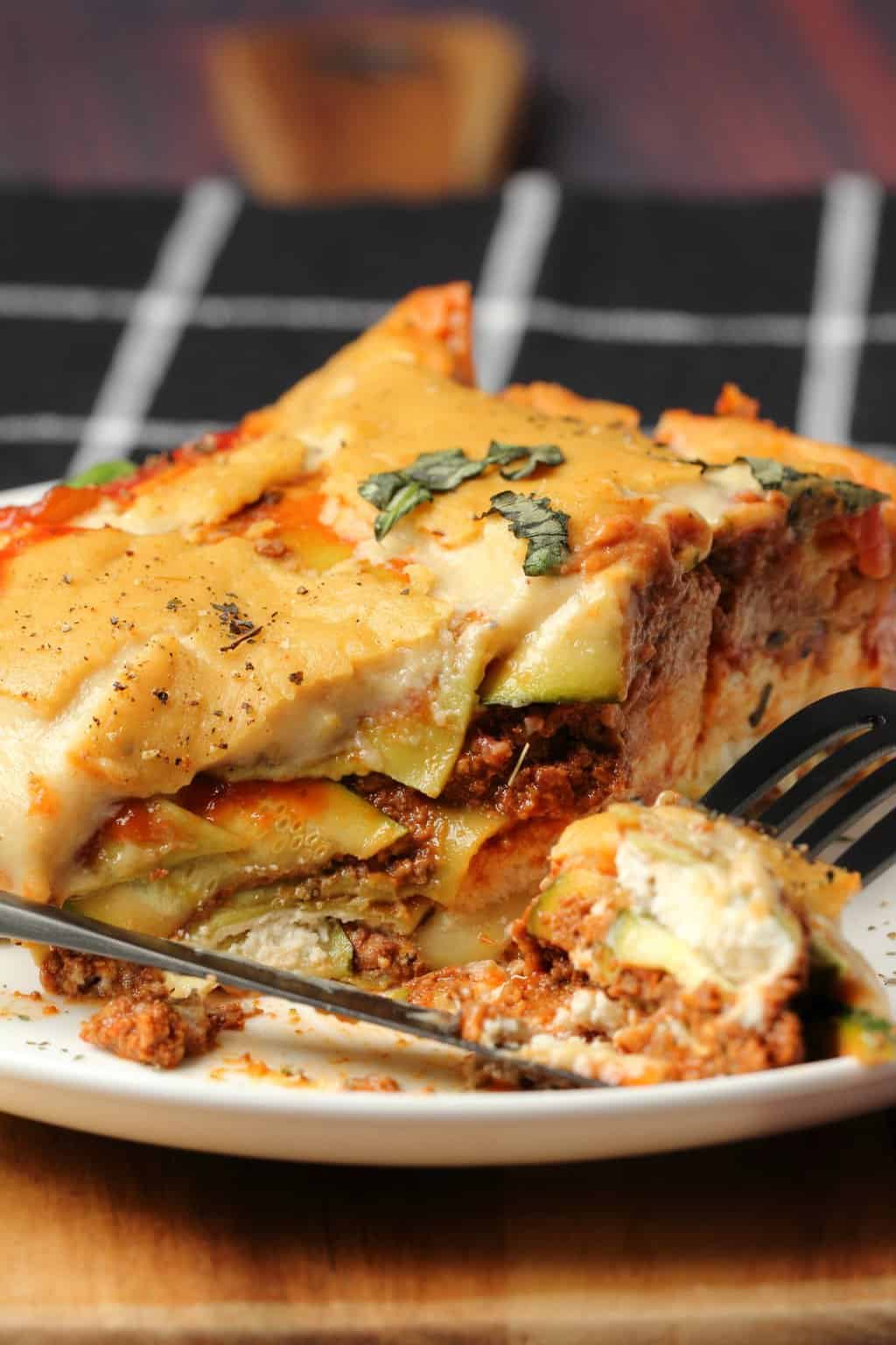 Tranche de lasagne végétalienne sur une plaque blanche avec une fourchette. 