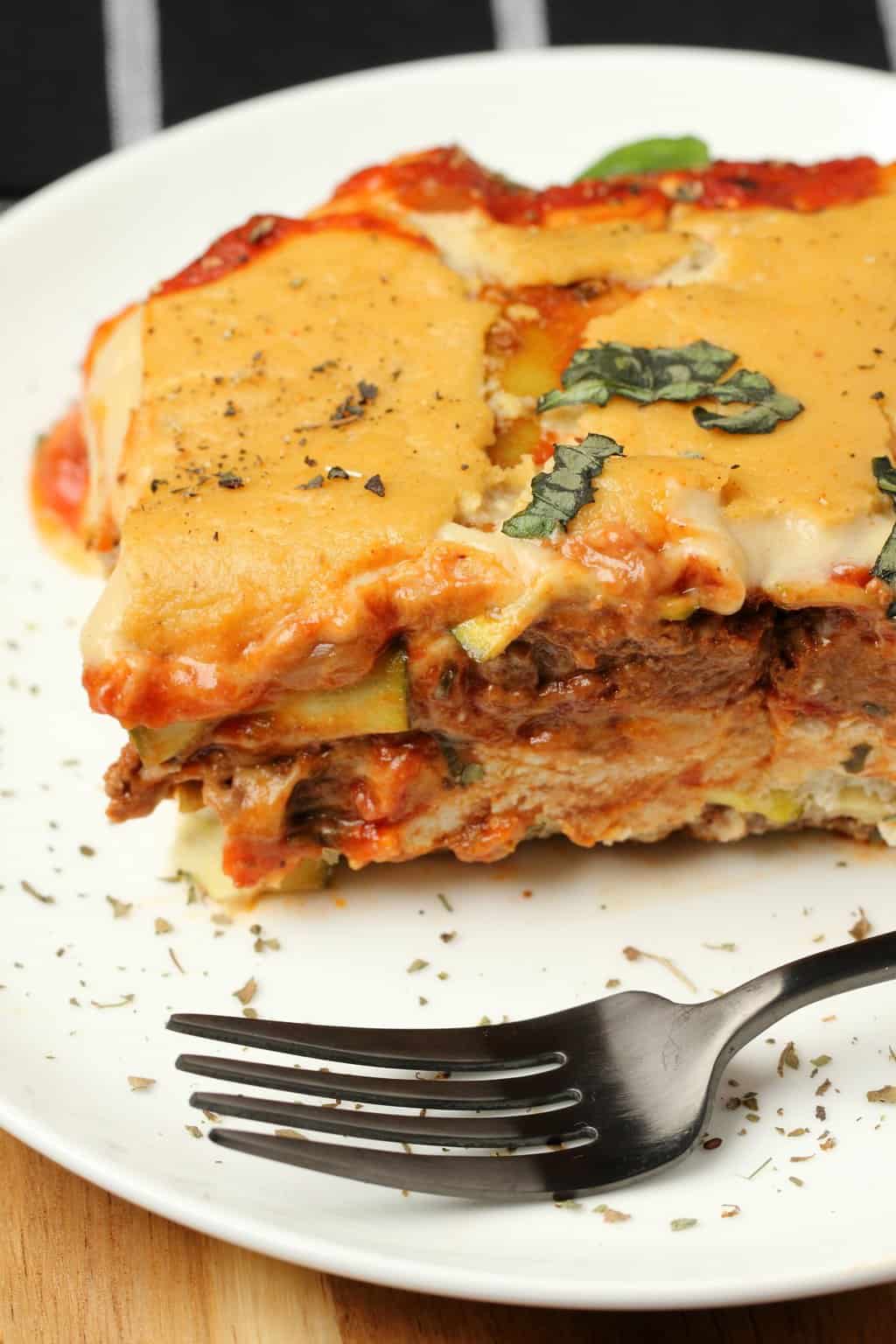 Tranche de lasagne végétalienne sur une plaque blanche avec une fourchette. 