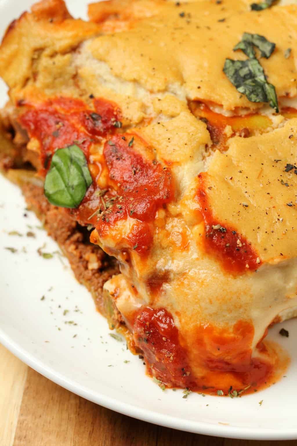 Tranche de lasagne végétalienne sur une plaque blanche. 