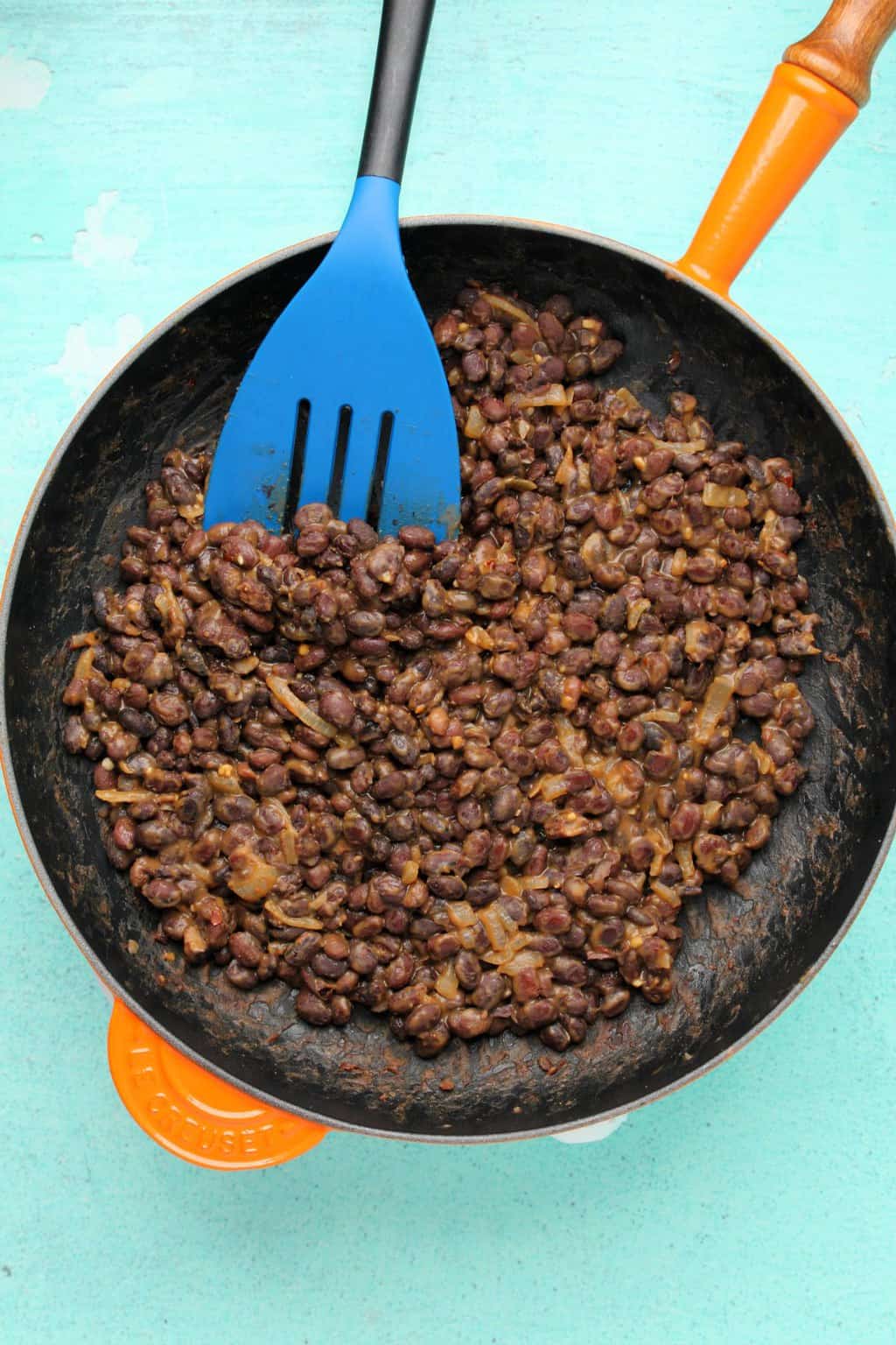Haricots noirs pour tacos végétaliens, avec oignons et épices mélangés dans une poêle. 