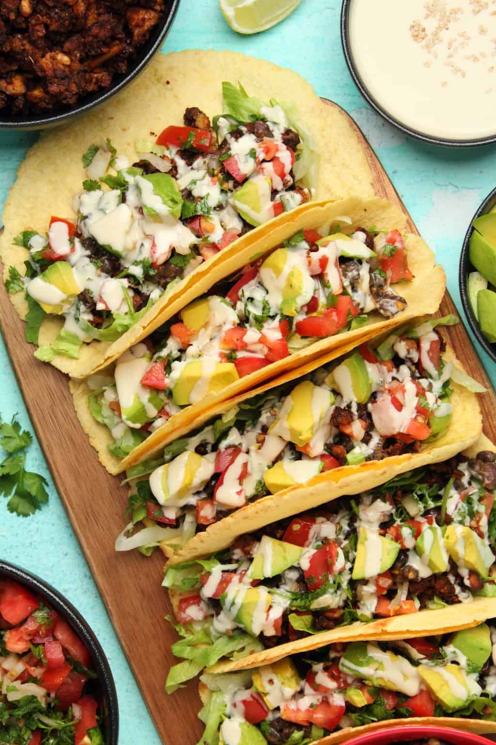 Tacos végétaliens alignés côte à côte sur une planche de bois. 