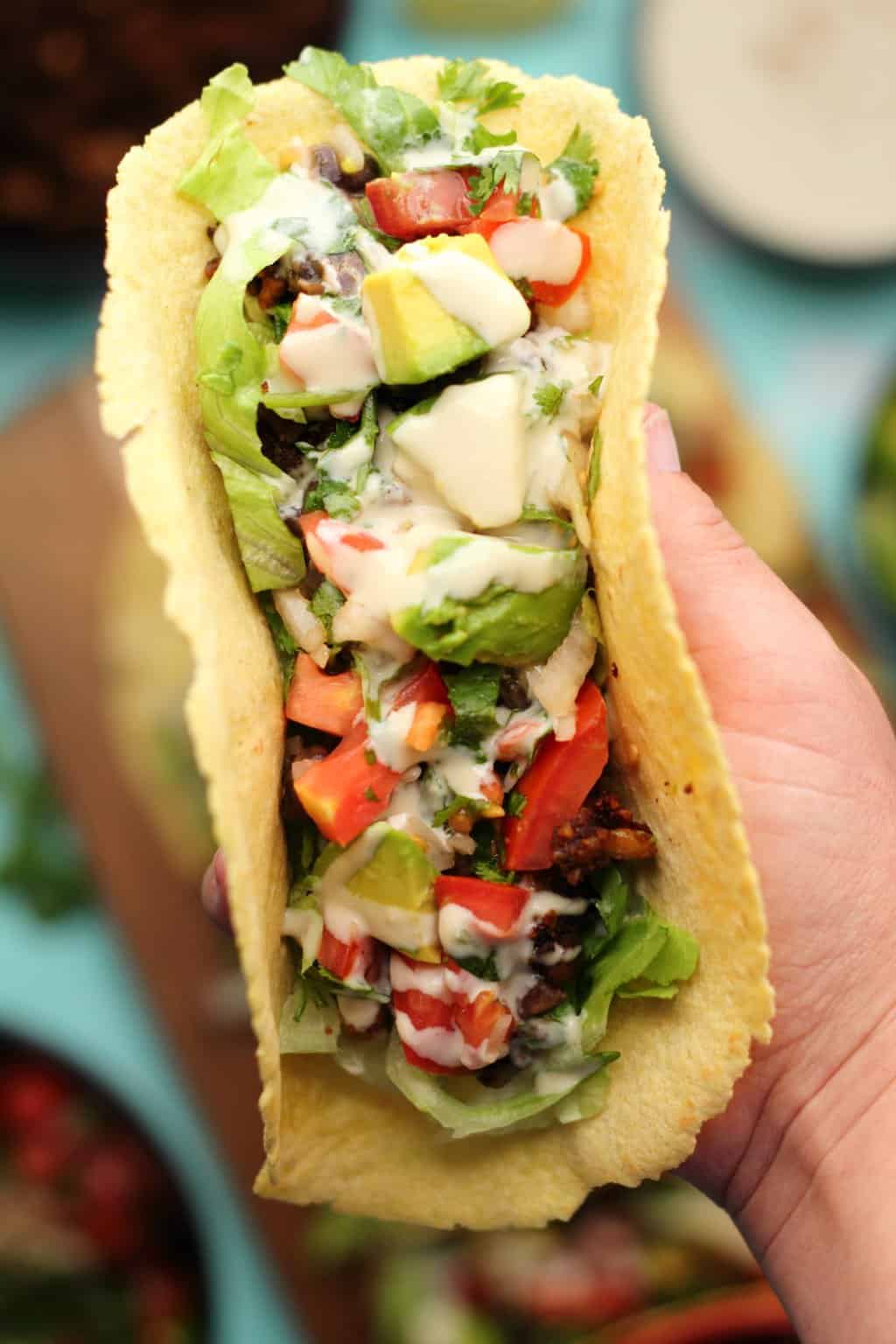 Taco végétalien farci de haricots noirs, viande de taco végétalienne, pico de gallo, avocat et sauce tahini. 
