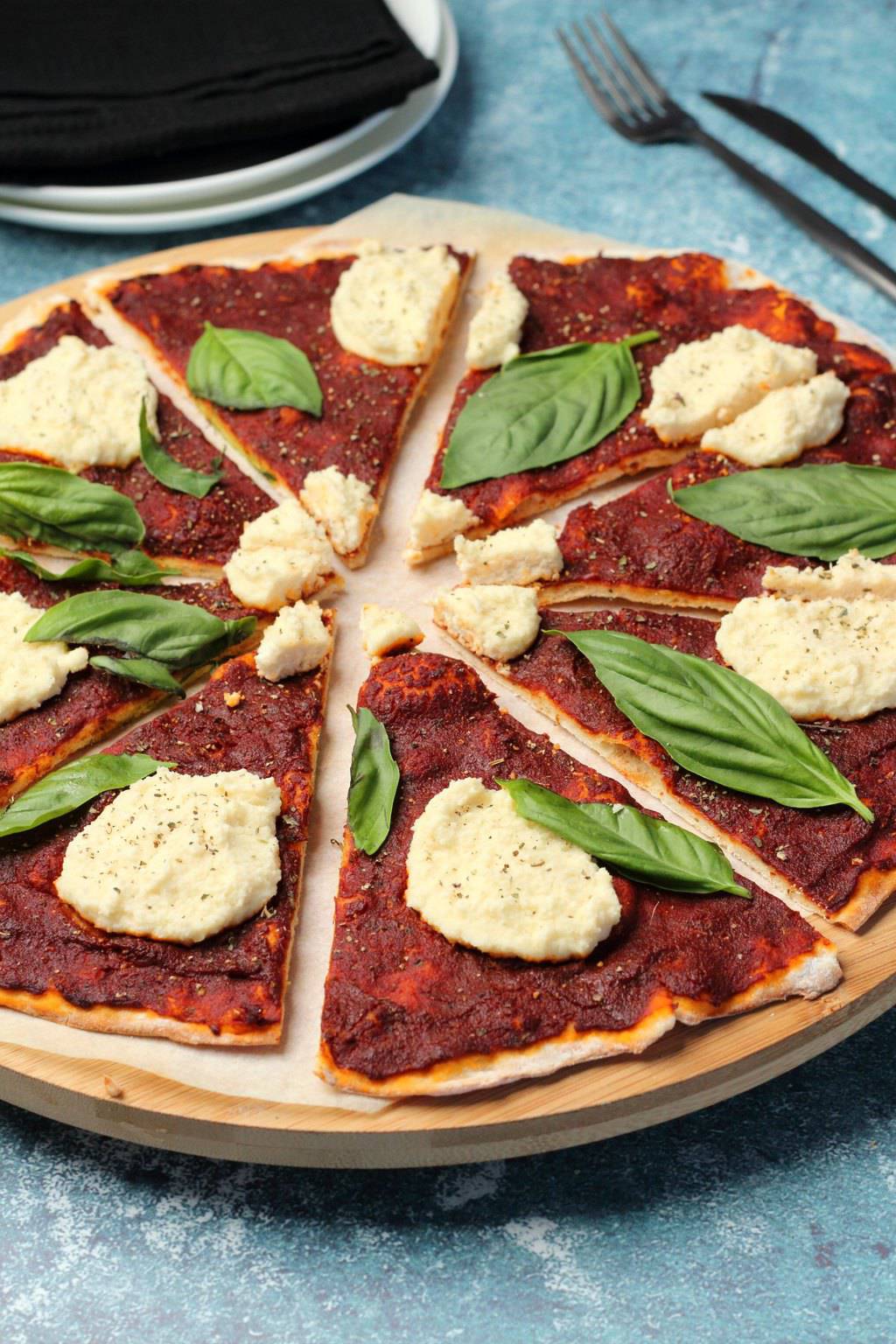 Pizza végétalienne garnie de ricotta végétalienne et de feuilles de basilic frais. 