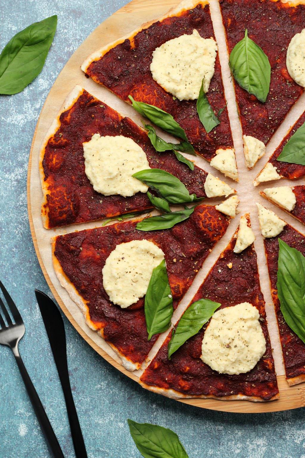 Pizza végétalienne garnie de ricotta végétalienne et de feuilles de basilic frais. 