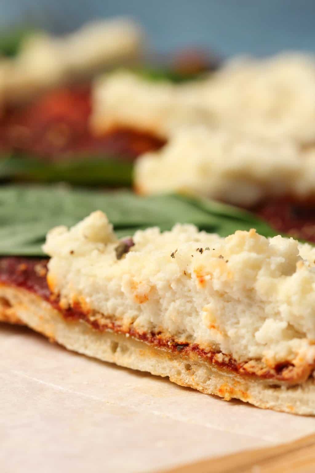 Pizza végétalienne garnie de ricotta végétalienne et de feuilles de basilic frais. 
