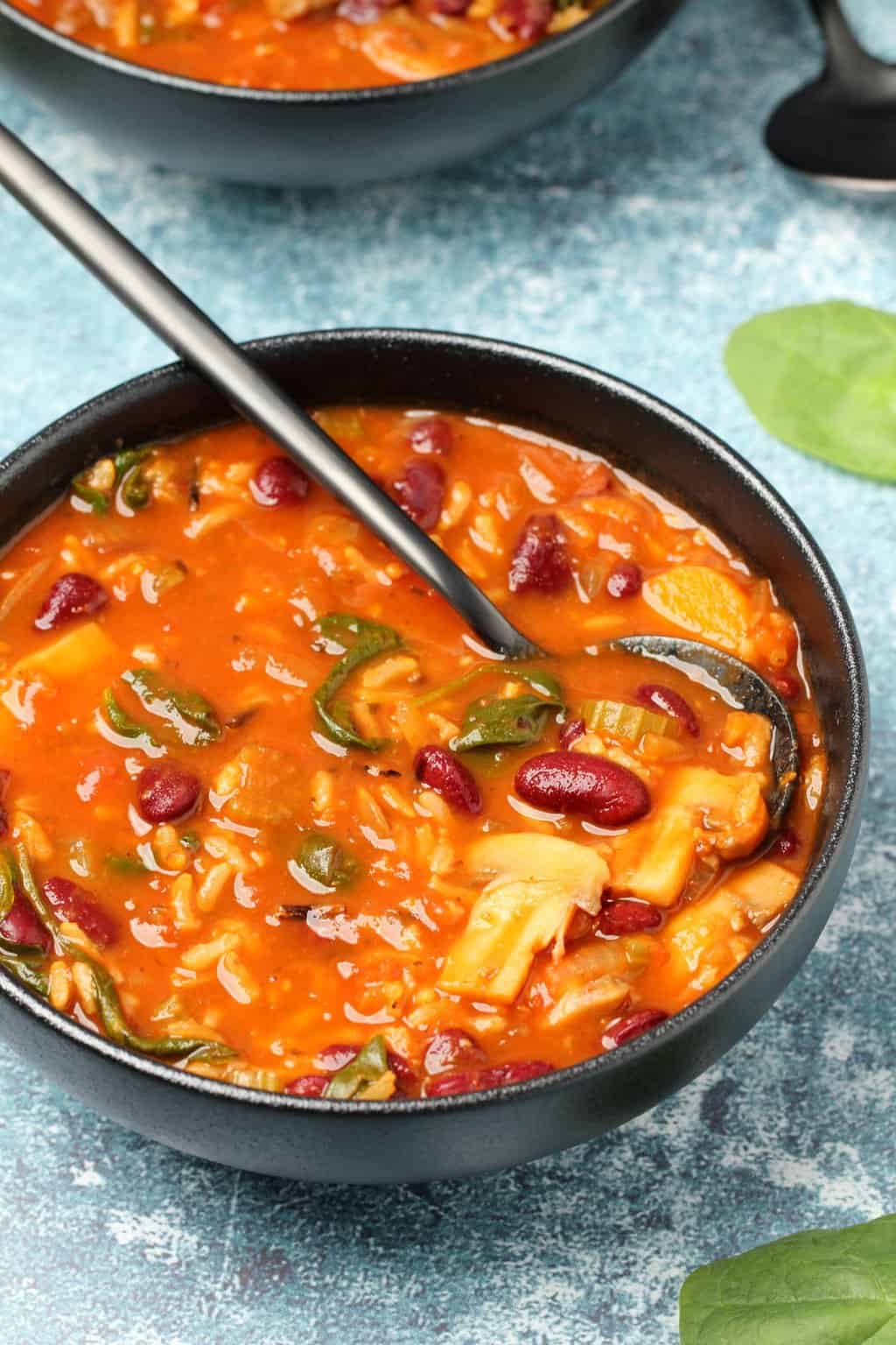 Soupe minestrone végétalienne dans un bol noir avec une cuillère.
