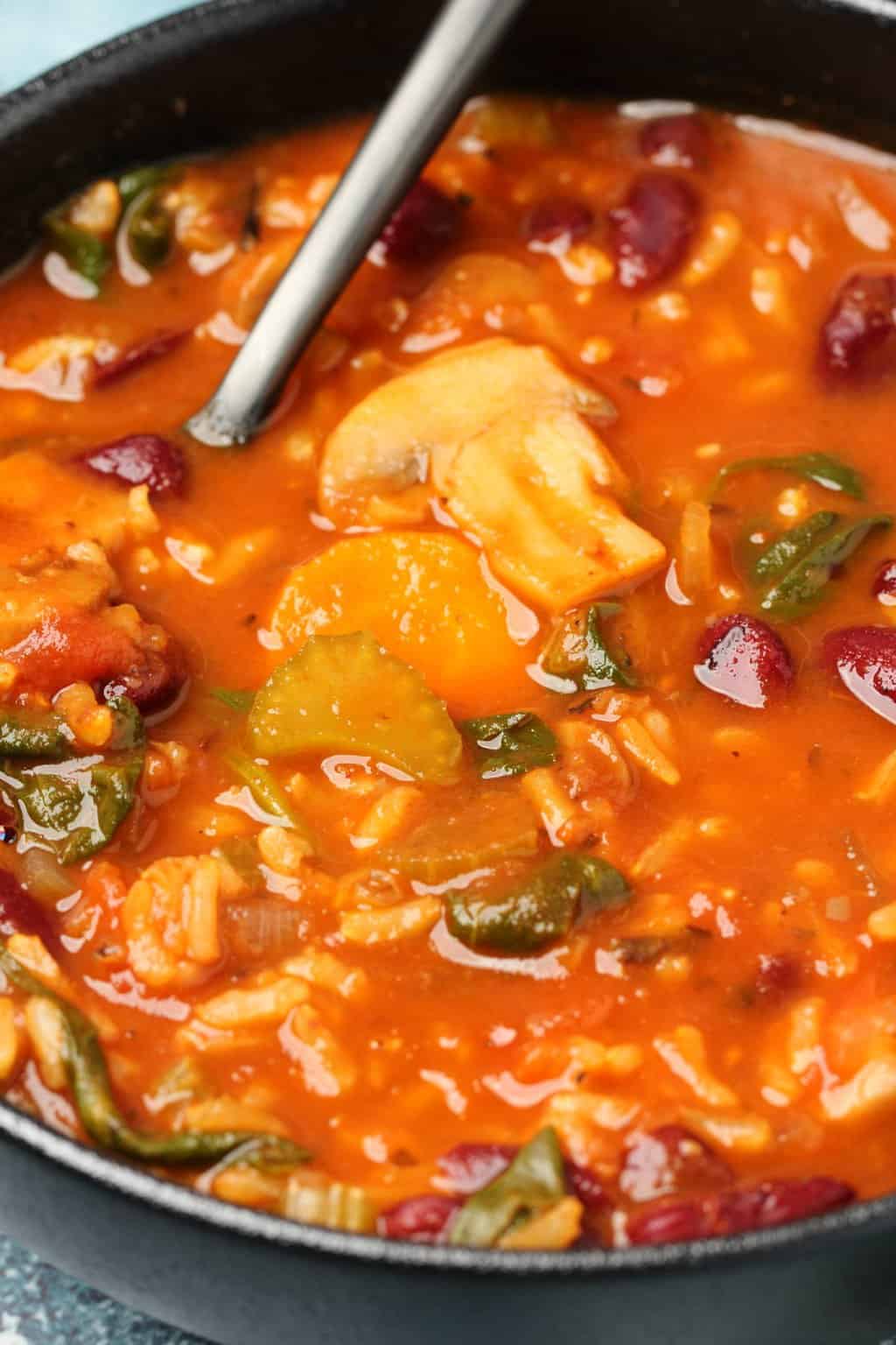 Soupe minestrone végétalienne dans un bol noir avec une cuillère.