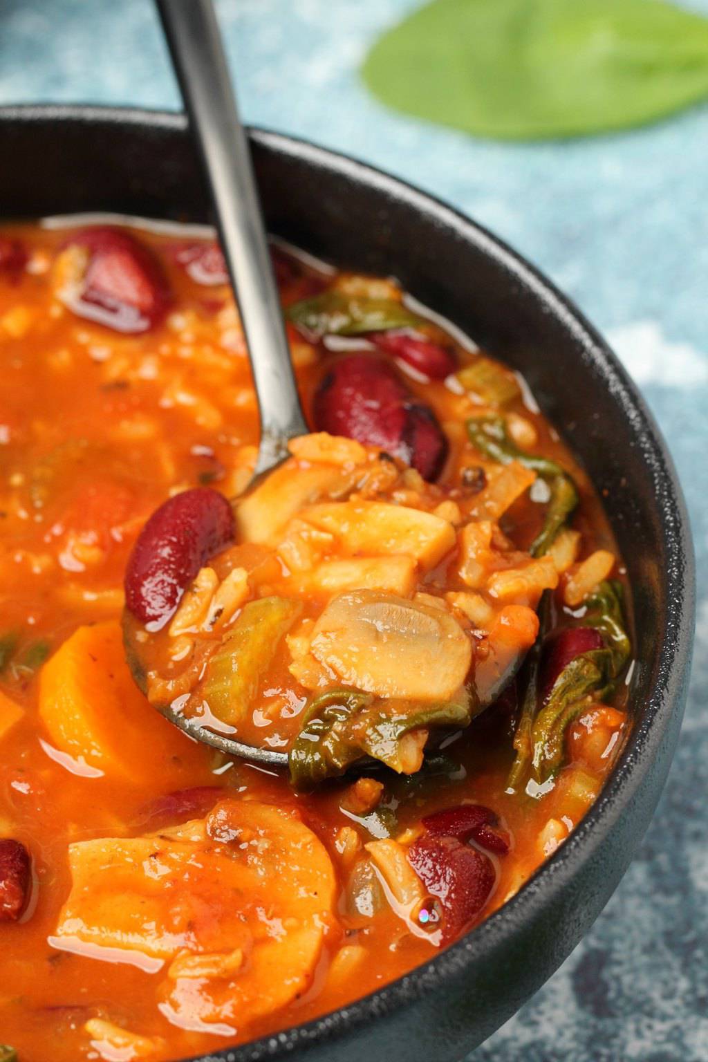 Soupe minestrone végétalienne dans un bol noir avec une cuillère.