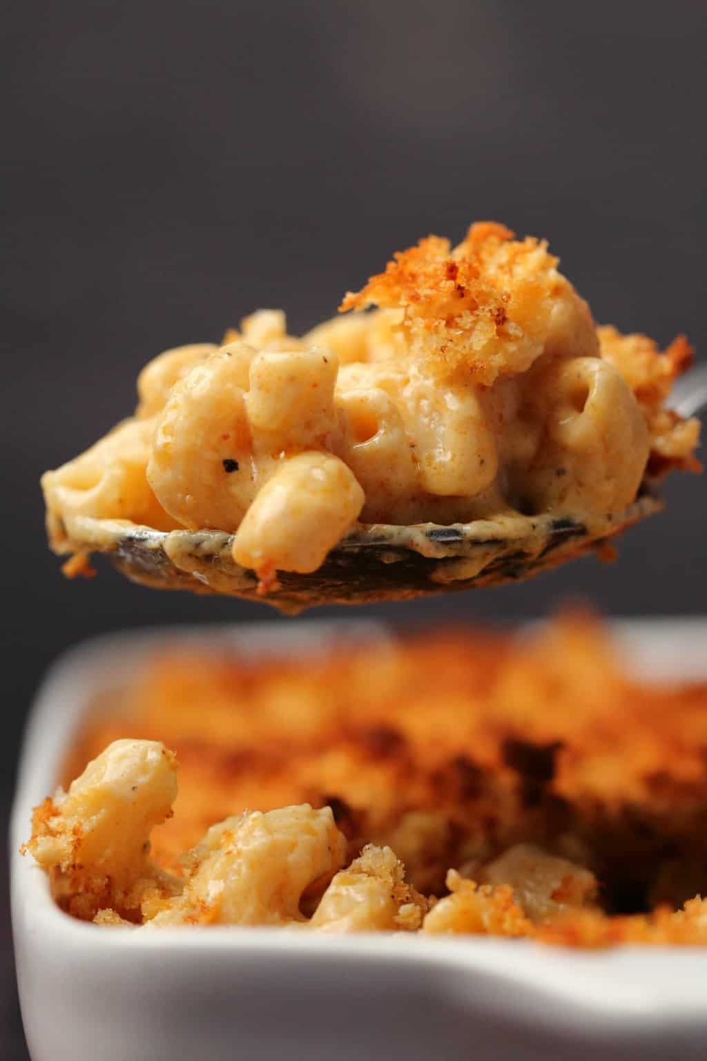 Macaroni au fromage végétalien Une grande cuillerée de macaroni au fromage végétalien sortant d'un plat blanc.