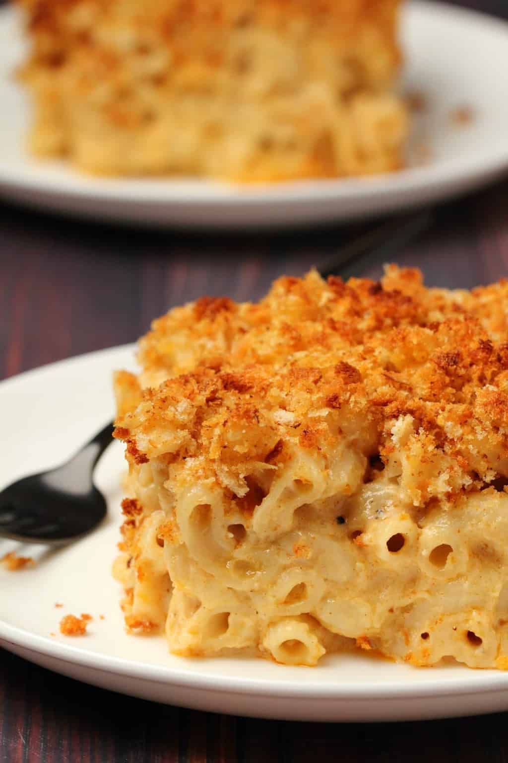 Macaroni au fromage végétalien au four Une tranche de mac et de fromage végétalien au four sur une plaque blanche avec une fourchette.