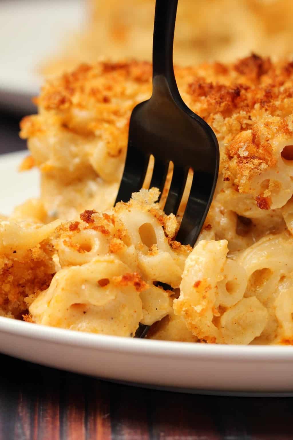 Macaroni au fromage végétalien au four Une tranche de mac et de fromage végétalien au four sur une plaque blanche avec une fourchette.