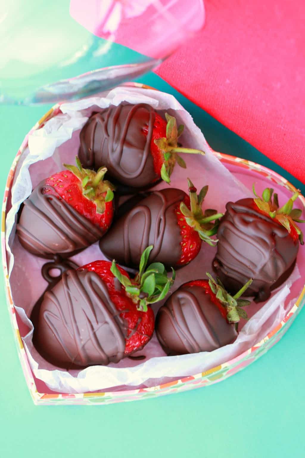 Fraises enrobées de chocolat végétalien dans une boîte en forme de coeur.