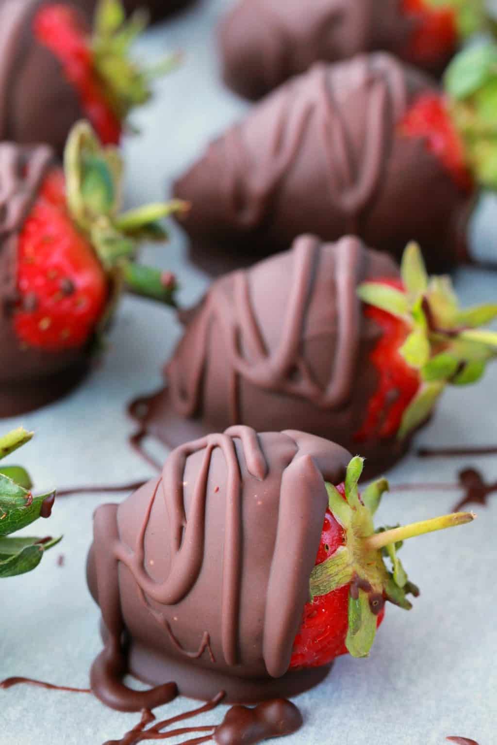 Fraises enrobées de chocolat végétalien sur papier parchemin.