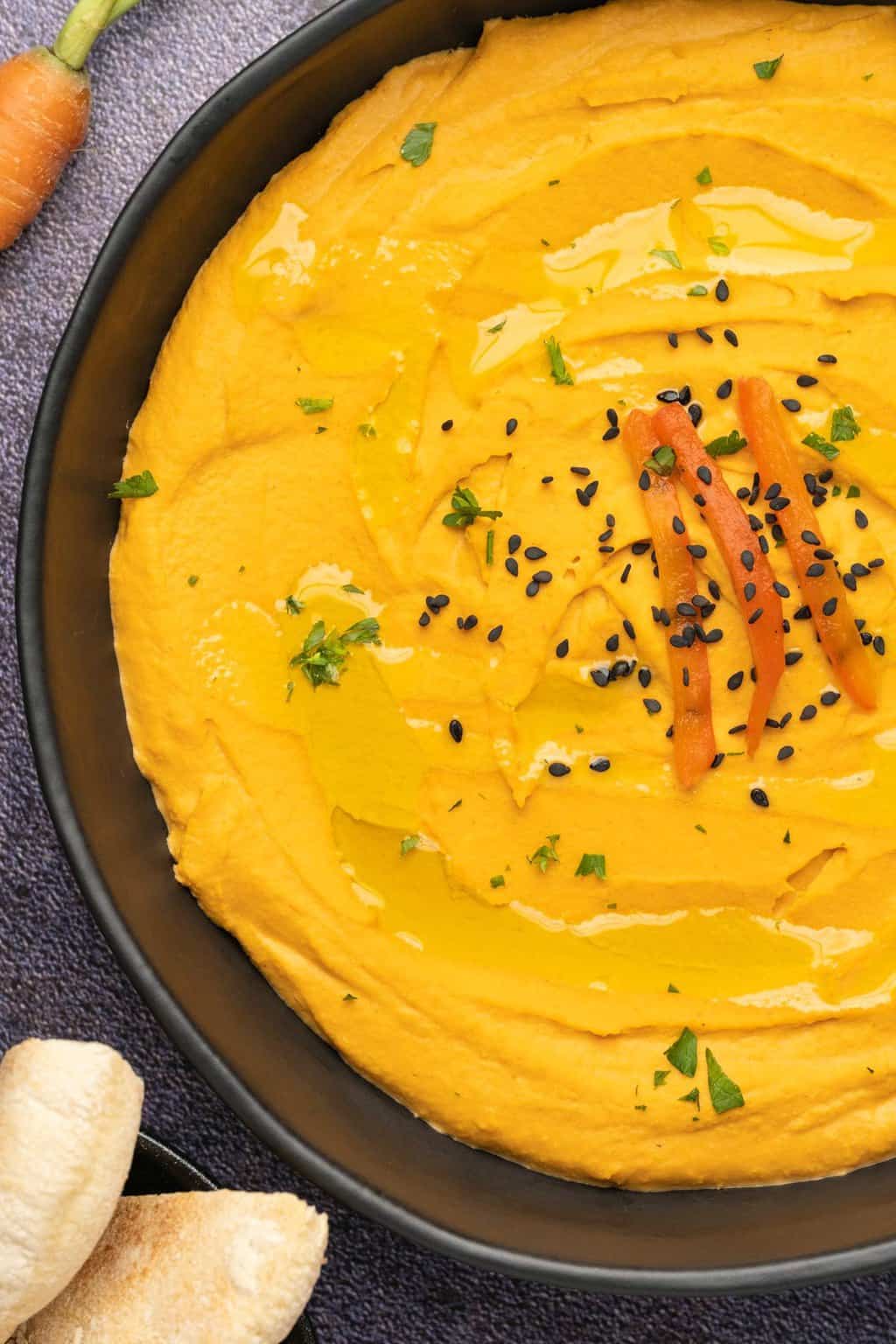 Houmous de poivron rouge rôti garni de graines de sésame et de persil.