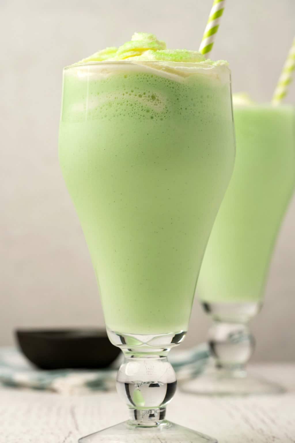 Shamrock végétalien secoue dans de grands verres avec des pailles à rayures vertes et blanches.