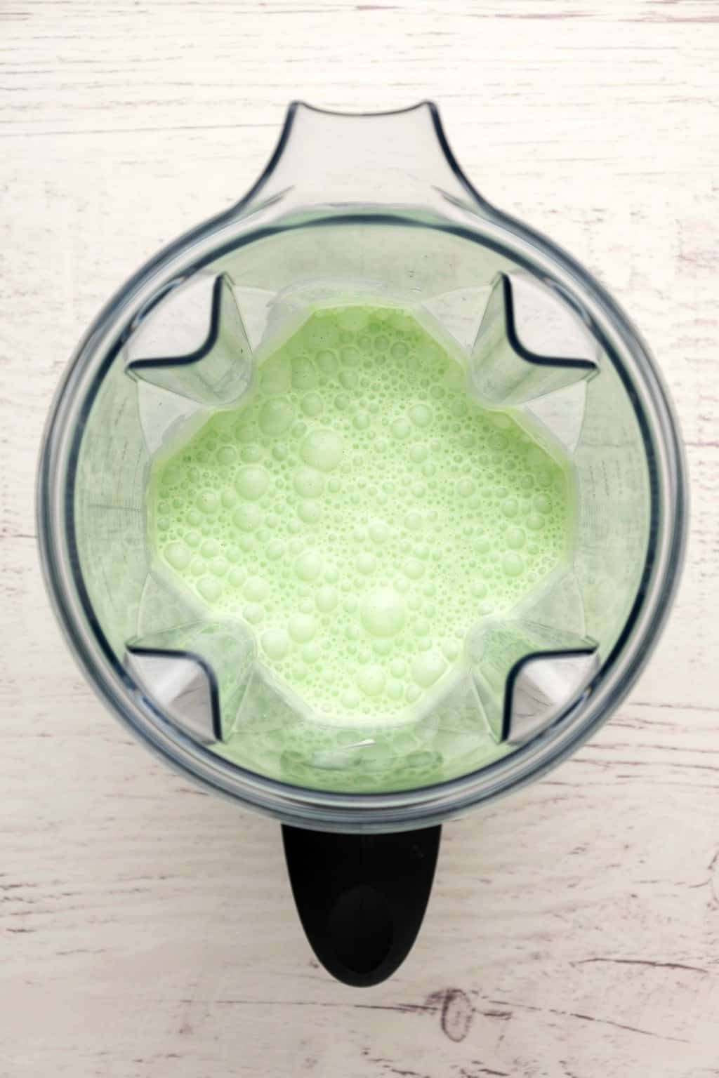 Pichet mélangeur avec milkshake vert menthe fraîchement mélangé.