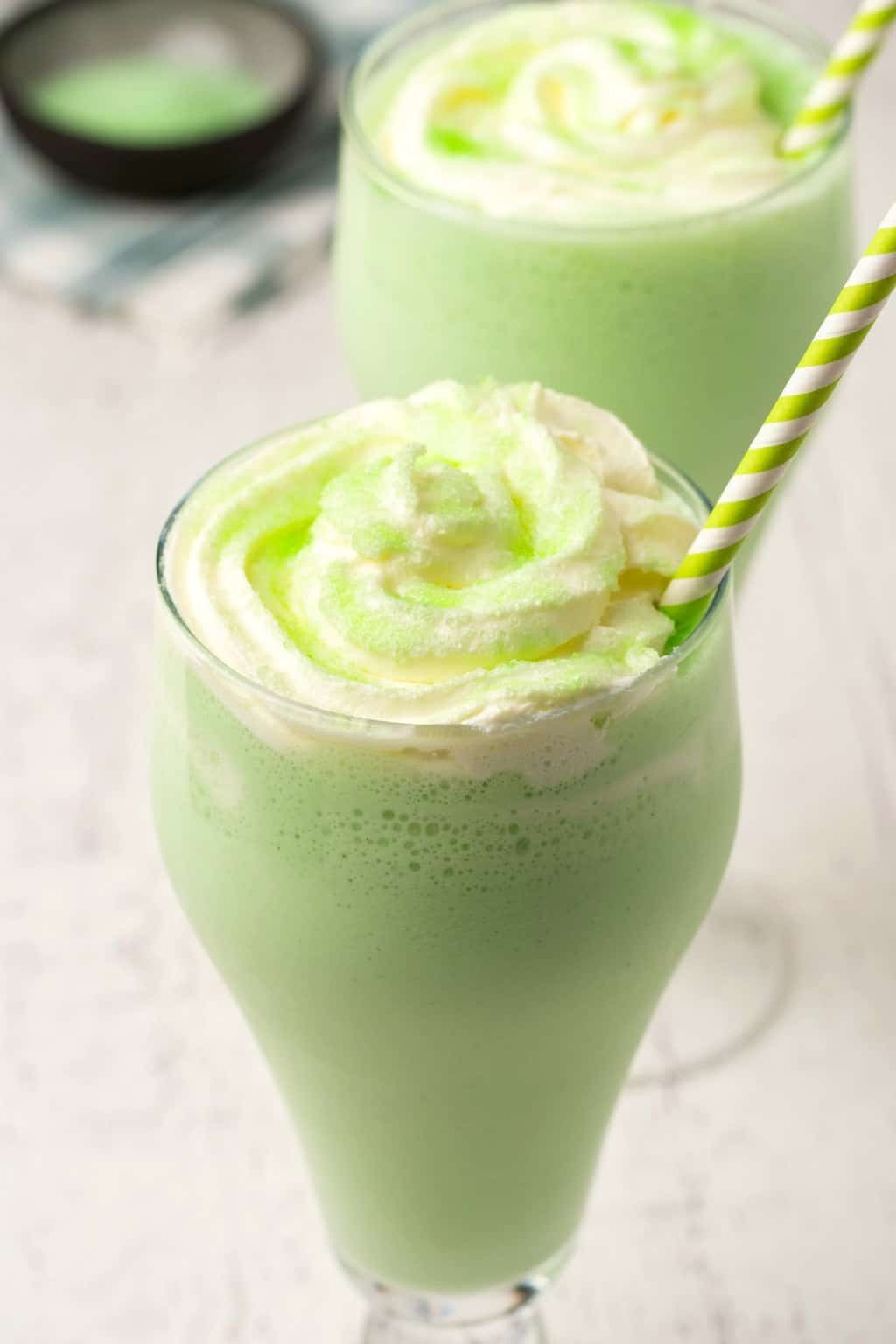 Shamrock végétalien secoue dans de grands verres recouverts de crème fouettée.