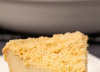 Gâteau au fromage sans produits laitiers (au four) – Loving It Vegan Tranche de gâteau au fromage sans produits laitiers sur une plaque blanche avec une fourchette à gâteau.