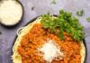 Lentilles à la bolognaise – Recette sans gluten Bolognaise aux lentilles garnie de parmesan végétalien dans un bol noir.