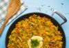 Paella végétalienne – Recette vegan Paella végétalienne garnie de quartiers de citron et de persil haché dans une poêle à paella noire.
