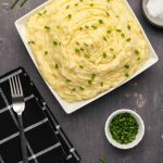Purée de pommes de terre végétalienne – Loving It Vegan Purée de pommes de terre végétalienne garnie de ciboulette hachée dans un plat blanc.