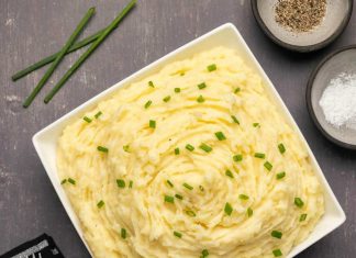 Purée de pommes de terre végétalienne – Loving It Vegan Purée de pommes de terre végétalienne garnie de ciboulette hachée dans un plat blanc.