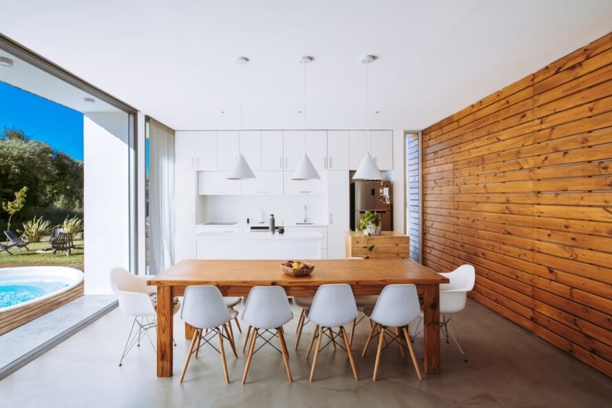table à manger en bois avec des chaises blanches près de la cuisine blanche