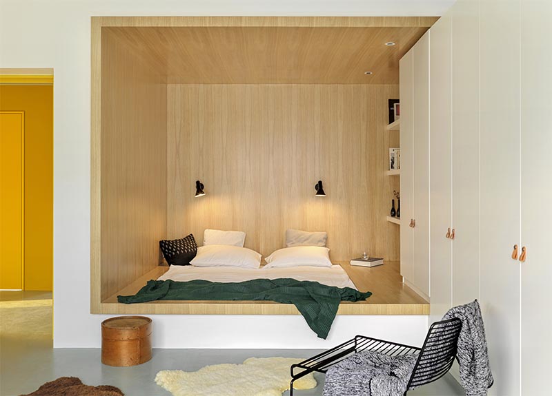 Au lieu d'avoir un lit autoportant, les concepteurs ont utilisé un petit coin de forme étrange positionné le lit dans la base de sa propre niche bordée de bois, permettant plus d'espace au sol grâce aux grandes fenêtres. #BedroomIdea #BedNook #BedNiche #BuiltInBed #InteriorDesign #ModernBedroom