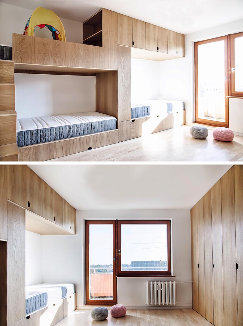 Cette chambre d'enfant moderne a de hauts plafonds, une porte coulissante en bois, un espace ouvert pour jouer, un mur d'armoires et un lit superposé conçu pour trois. #BunkBed #KidsRoom #ChildrensBedroom #Cabinets #BedDesign