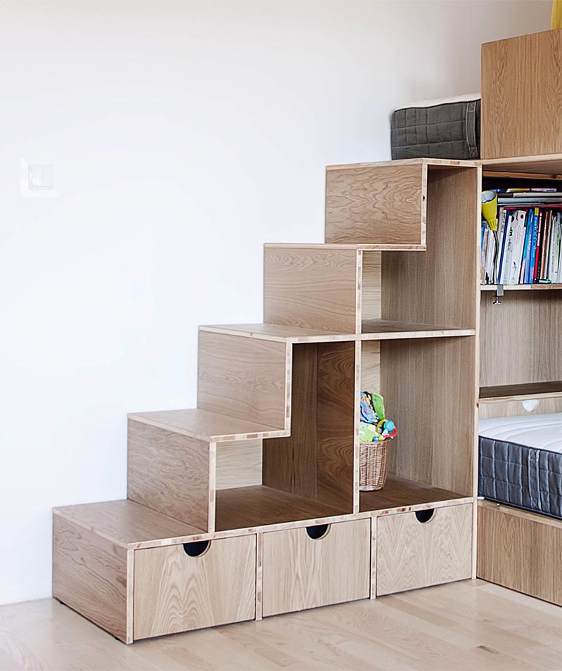 La conception des lits superposés, a les trois lits à différents niveaux, avec le lit supérieur accessible via un escalier qui a des étagères ouvertes et sert également de stockage de jouets. #BunkBedStairs #BunkBed #StairsWithStorage #KidsBedroom