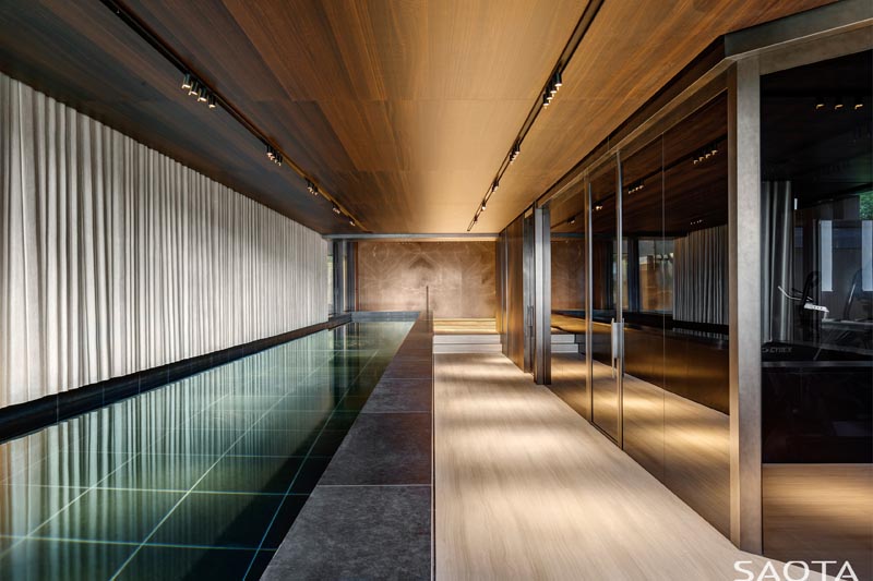 Au sous-sol de cette maison moderne, il y a une deuxième piscine longue et étroite, positionnée à côté d'un mur de fenêtres. #Sous-sol #Piscine