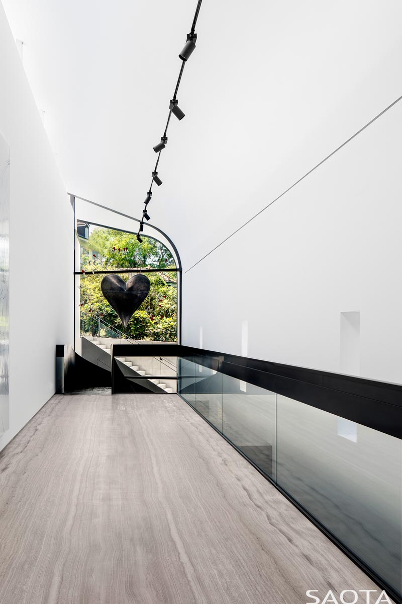 Au sommet de l'escalier de cette maison moderne se trouve une fenêtre avec vue sur le jardin, et dont la forme suit la ligne du plafond incurvé. #CurvedWindow #Windows #ModernHouse