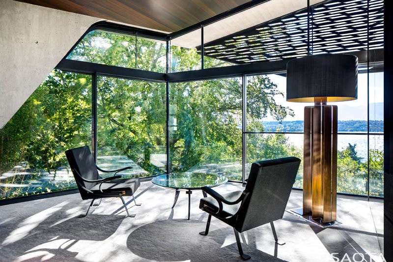 Ce bureau à domicile moderne profite des vues spectaculaires et profite de l'ombre des arbres et de l'écran perforé à l'extérieur de la maison. #ModernHomeOffice #GlassWalls