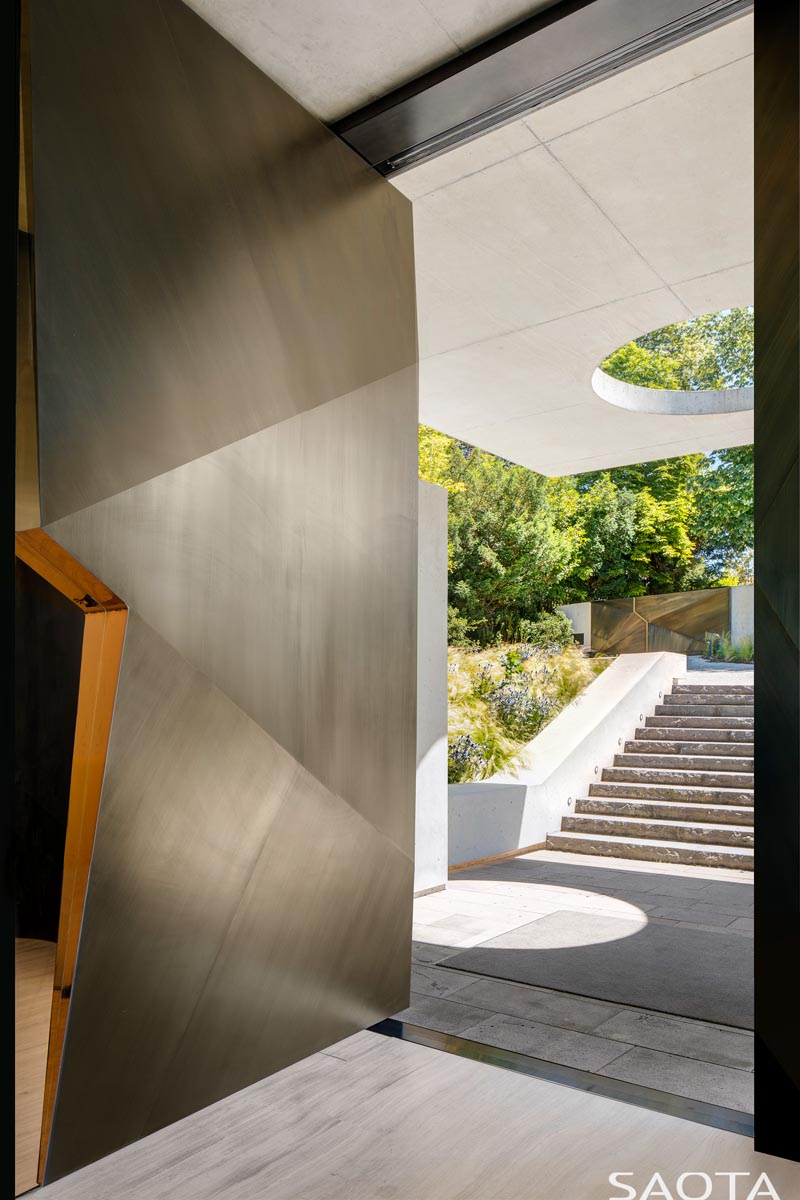 Cette porte d'entrée pivotante moderne et grande, revêtue de cuivre, a des angles qui créent un sentiment d'intérêt au moment où vous franchissez la porte. #CopperFrontDoor #FrontDoor #DoorIdeas