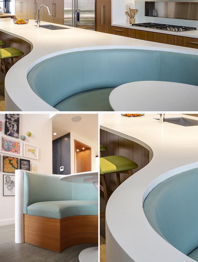 Le comptoir de l'île Corian blanc sur mesure dans cette cuisine moderne, a une forme rectangulaire à une extrémité, avant de passer à une conception incurvée divisée qui s'enroule autour des banquettes bleu doux qui composent le coin petit-déjeuner intégré. #KitchenDesign #ModernKitchen #BreakfastNook #BanquetteSeating #KitchenIsland