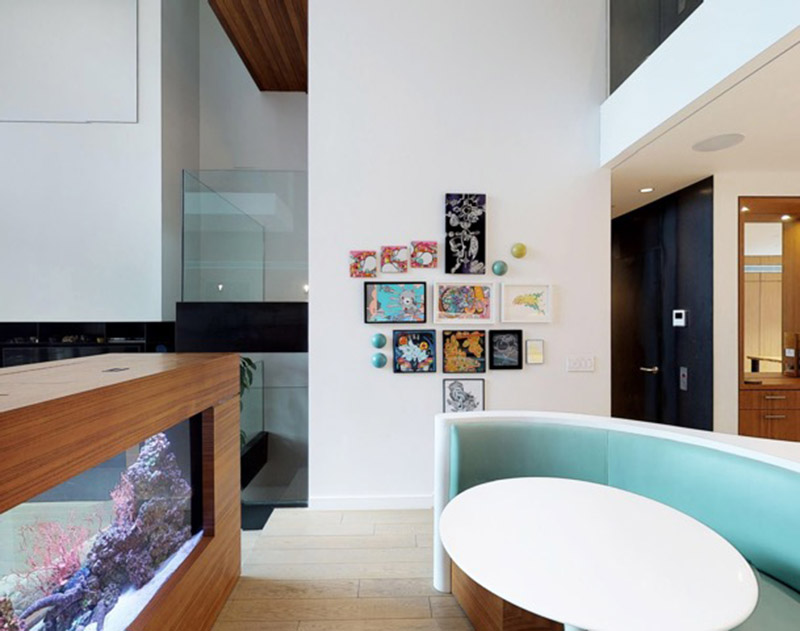 Le comptoir de l'île Corian blanc sur mesure dans cette cuisine moderne, a une forme rectangulaire à une extrémité, avant de passer à une conception incurvée divisée qui s'enroule autour des banquettes bleu doux qui composent le coin petit-déjeuner intégré. #KitchenDesign #ModernKitchen #BreakfastNook #BanquetteSeating #KitchenIsland