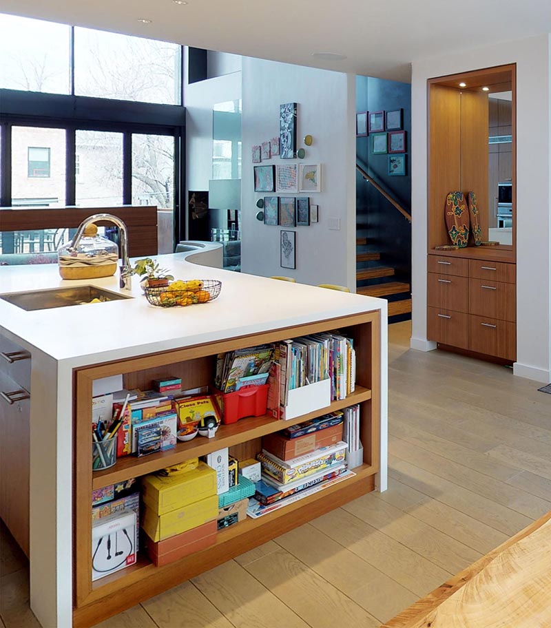Cet îlot de cuisine moderne comprend une étagère intégrée, un évier encastré et un coin petit-déjeuner incurvé. #KitchenIsland #KitchenDesign #ModernKitchen #KitchenShelving