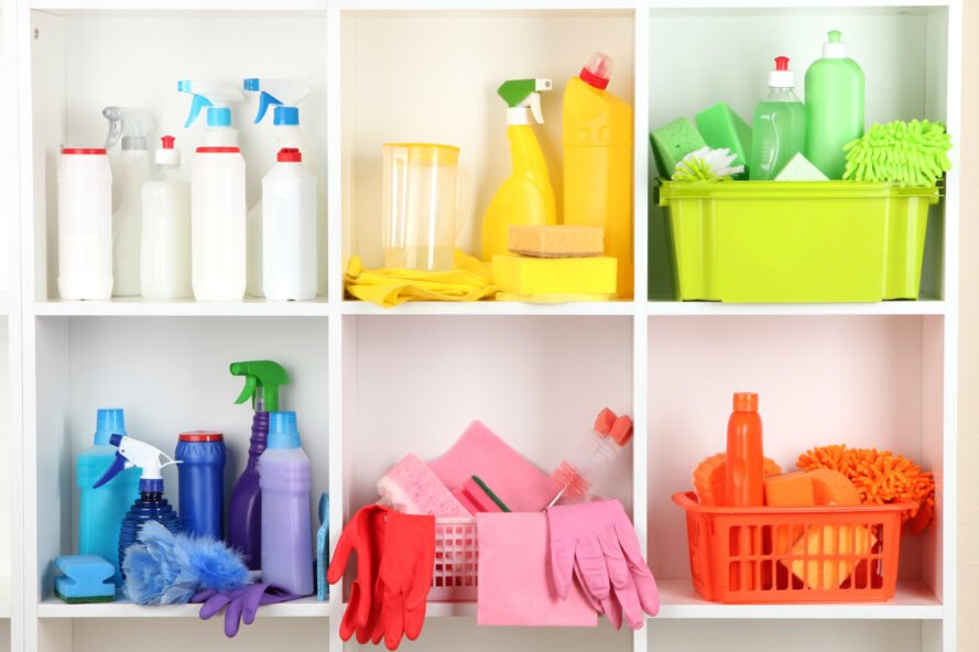 étagères blanches remplies de bouteilles en plastique colorées de nettoyants ménagers