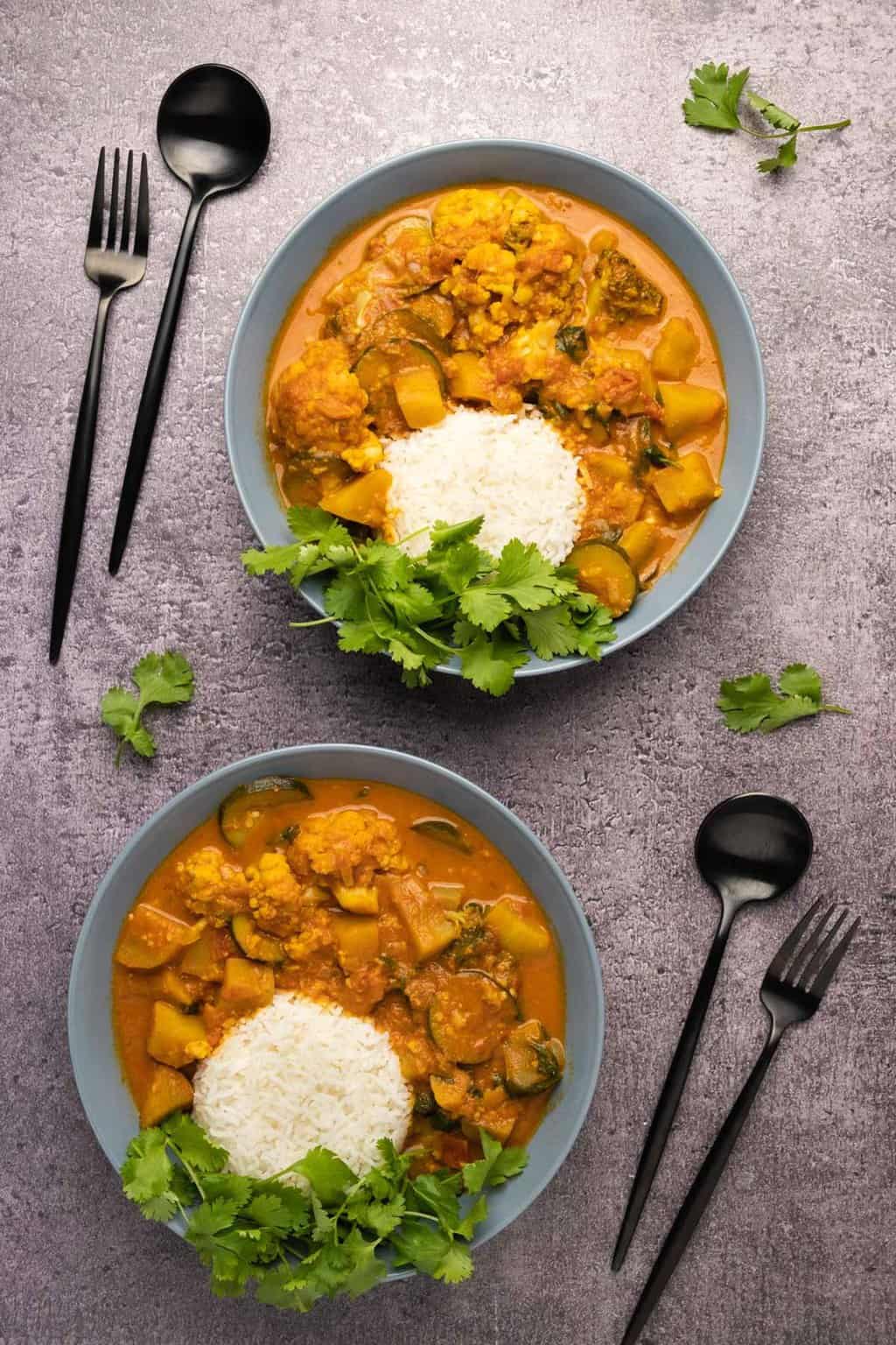 Curry végétalien avec riz basmati et coriandre fraîche dans des bols bleus.