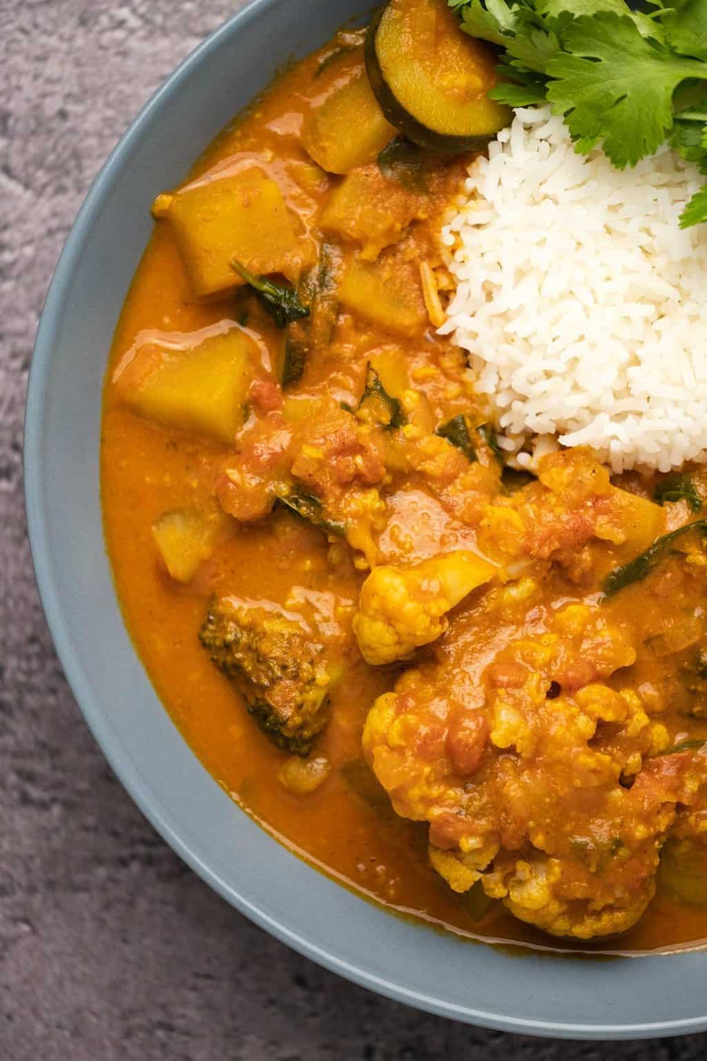 Curry végétalien avec riz et coriandre dans un bol bleu.