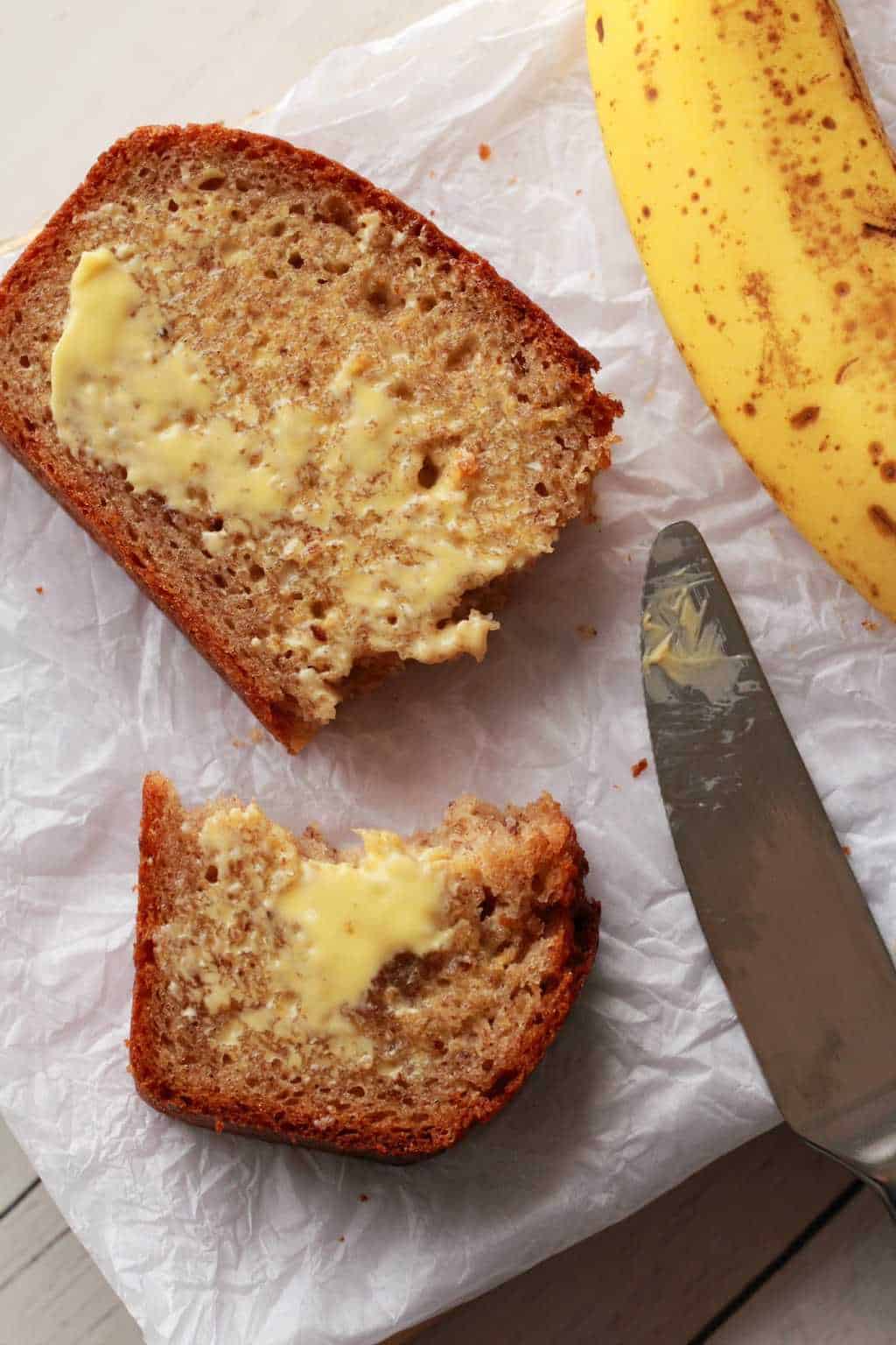 Tranche de pain aux bananes beurrée cassée en deux.