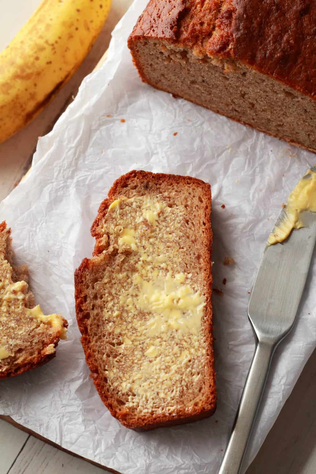 Tranche de pain aux bananes beurrée avec un couteau à beurre.