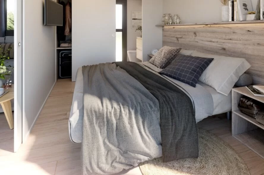 chambre principale avec grand lit recouvert de draps gris