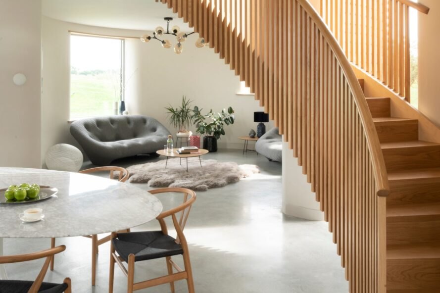 canapé et chaise gris derrière un escalier circulaire en bois